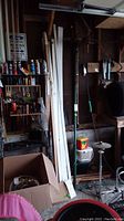Wider photo of the storage area where the limb saw is located, showing surrounding tools and wood pieces for context.