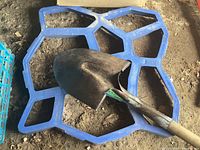 Walk Maker blue plastic concrete mold with shovel on top, mold measures 24x24 inches.