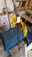 Overview of shovels leaning over bags of yellow utility salt, showing shovel handles and salt bags behind.