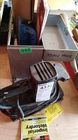 Black Craftsman electric hand sander with cord coiled, placed near a metal divider box.