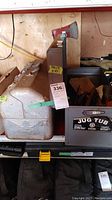 Photo of large metal toolbox and black plastic container with assorted tools and an axe behind.