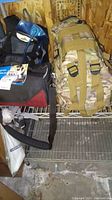 Camera bag and survival backpack on wire rack shelf, hydration tube visible from backpack