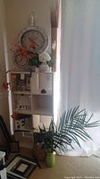 Wide view of shelving unit with wall clock, faux flowers, dried grasses, and decorative items