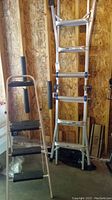 Photo showing the 4-foot folding ladder with three black steps and handrail, alongside 14-foot extension ladder leaning against a wooden wall.