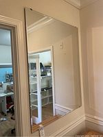 Large frameless rectangular wall mirror mounted on wall.
