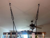 Front view of rectangular metal hanging pot rack suspended from ceiling by four chains