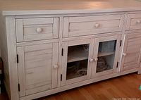Front view showing three drawers and four-door cabinet (including two glass-panel doors)