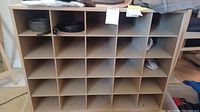 Front view of the pressed wood shoe rack showing the 24 square compartments organized in a 4 by 6 grid.