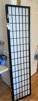 Single closed panel standing upright showing black frame with white translucent grid panel