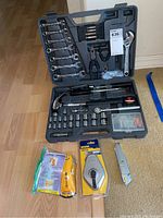Full view of Performance Tool socket wrench set opened to show contents along with Stanley razor knife, Zircon stud finder, and Irwin chalk line