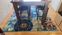 Wide view showing the rug under a wooden table with chairs, displaying the floral pattern and size.