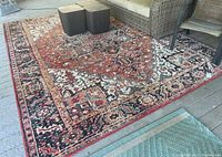 Full view of the large area rug on a residential deck showing overall pattern and condition.