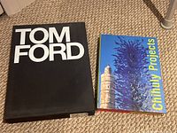 Two hardcover art and fashion books placed on carpeted floor; one titled 'TOM FORD' with a black cover and the other 'Chihuly Projects' with a colorful blue cover.