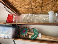 Glass vases, red glass pitcher, green wooden garden sign with flower decor on shelf