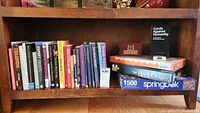 Books on shelf with various titles and games including a boxed puzzle and card game