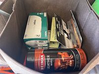Top view inside fabric container showing various boxed light bulbs, battery packs, and a canister of Weiman Leather Wipes.