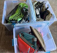 Clear plastic containers holding the kayak, seat, life vest, and accessories in garage setting.