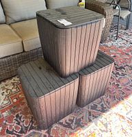 Three dark brown outdoor modular storage cubes stacked with visible outdoor wear and dirt.