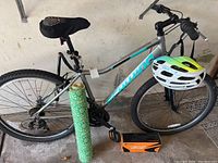 Full side view of Schwinn aluminum women's bicycle showing frame, helmet on handlebar, yoga mat beside bike, foot pump on ground near front wheel.