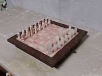 View of the onyx chess set arranged on the square playing board within the wooden frame showing the pieces and board pattern.