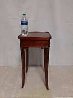 Front view of vintage mid century end table with water bottle on top for scale