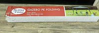 Box of Alpine Cuisine 10x10 ft PE folding gazebo showing brand, size and green color.