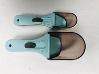 Photo showing two light blue adjustable measuring spoons with sliding capacity adjustment, one larger and one smaller.