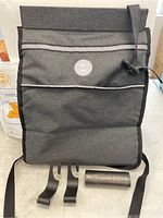 Front view of gray car garbage bag with two black hooks and disposable garbage bag roll displayed in front.