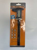 Front view of the digital caliper in original packaging showing the product and included battery.