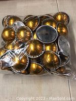 Bag of 50 golden Nespresso coffee pods grouped together.