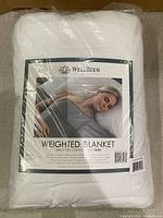 Packaged white WellBeen Natural Therapy weighted blanket with product label, showing branding and product image.