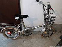 Full side view of the silver Bridgestone Picnica folding bicycle showing small wheels, front basket, rear rack and fenders.