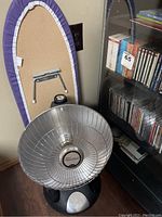 Photo of black wood glass CD cabinet filled with classical music CDs, countertop ironing board, and Presto HeatDish heater in front