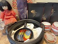 Overview showing cast iron pot, fry pan with colorful spoons, sushi trays, bowls, and Japanese dolls