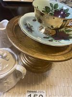 White embossed porcelain cream and sugar set beside gold pedestal plate with Japanese floral teacup and saucer on top
