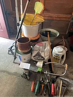 Full view of the hand cart, buckets, gardening gloves, ceramic pot, garden tools, basin and gardening products.