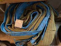 Rolled and folded heavy duty tarp showing blue reinforced edges and metal grommets along the edge.