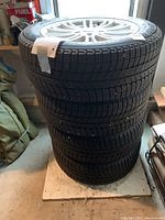 Stack of four mounted tires on rims in storage area