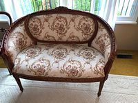 Front view of ornate English inspired loveseat showing carved wood frame and floral upholstery.