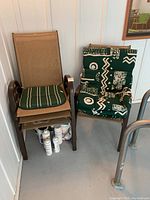 Four outdoor chairs stacked and arranged showing two with green patterned cushions and two with green striped cushions, along with bottles stored underneath.
