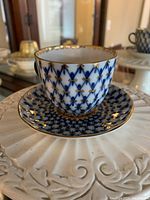 Close-up photo of the teacup on the saucer showing the cobalt blue lattice and gold detailing.
