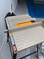 Metal surface of Ryobi table saw showing blade slot cover and Ryobi logo.