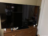 Samsung 54-inch TV and wooden cabinet below it, showing overall appearance and condition.