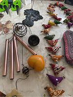 Overview photo showing metal wind chimes, a yellow soapstone heart, carved soapstone items, and a row of fabric bird decorations.