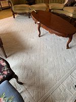 Full view of cream rug under coffee table and sofas