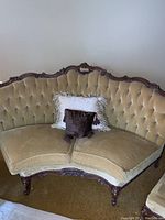 Front view of two-seater loveseat with carved wooden frame and tufted light brown velvet upholstery. Includes two decorative pillows.