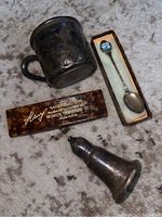 Photo showing all three items: tarnished child's cup, souvenir spoon in box, and silver shaker on carpeted surface.