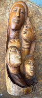 Full view of the carved wooden statue showing four faces arranged vertically.