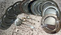 Top view of twelve Rogers marked silver plate plates engraved with B and four silver plated serving utensils including two ladles, a pierced spoon and sugar tongs on carpet
