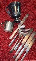 View of the sterling child's cup, Simpson Hall & Miller treble plate cup, and assorted forks and knives
